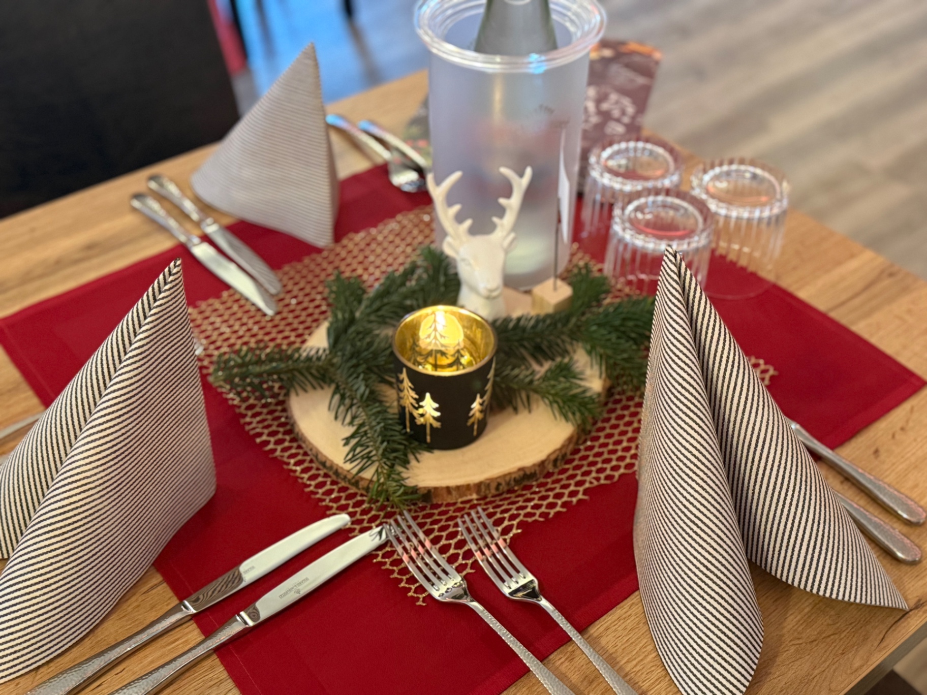 Weihnachtliche Tischdekoration mit Tannengrün, Kerze und rotem Tischläufer